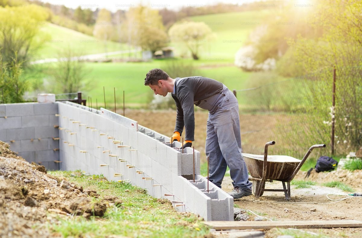 Tradesman laying concrete blocks on a new retaining wall