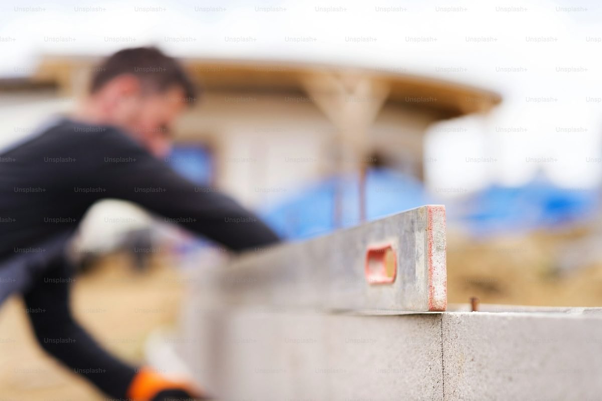 Spirit level being checked across a course of retaining wall blocks